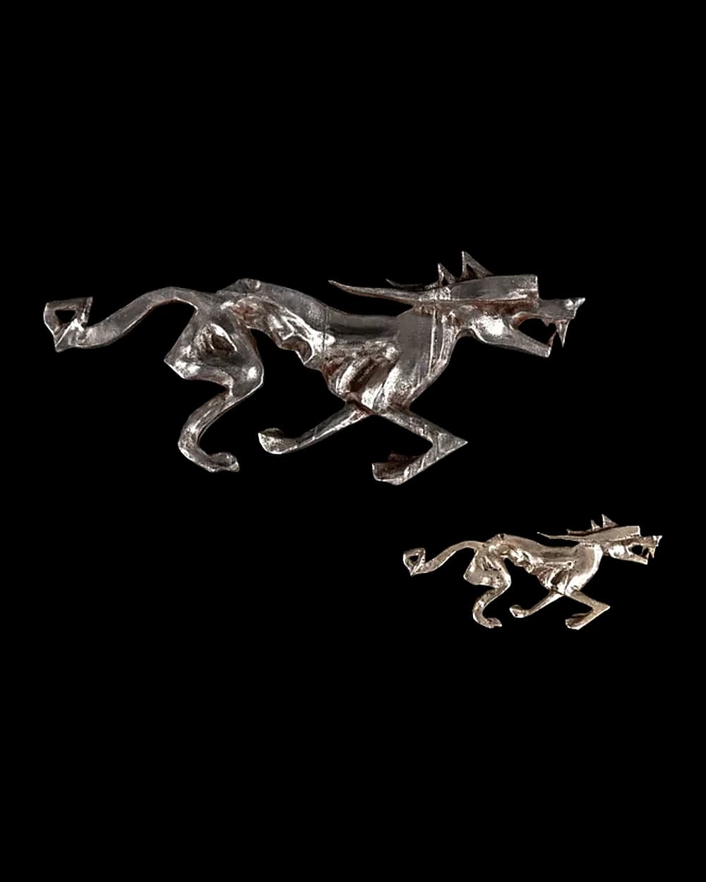 Two cast silver dogs at a run