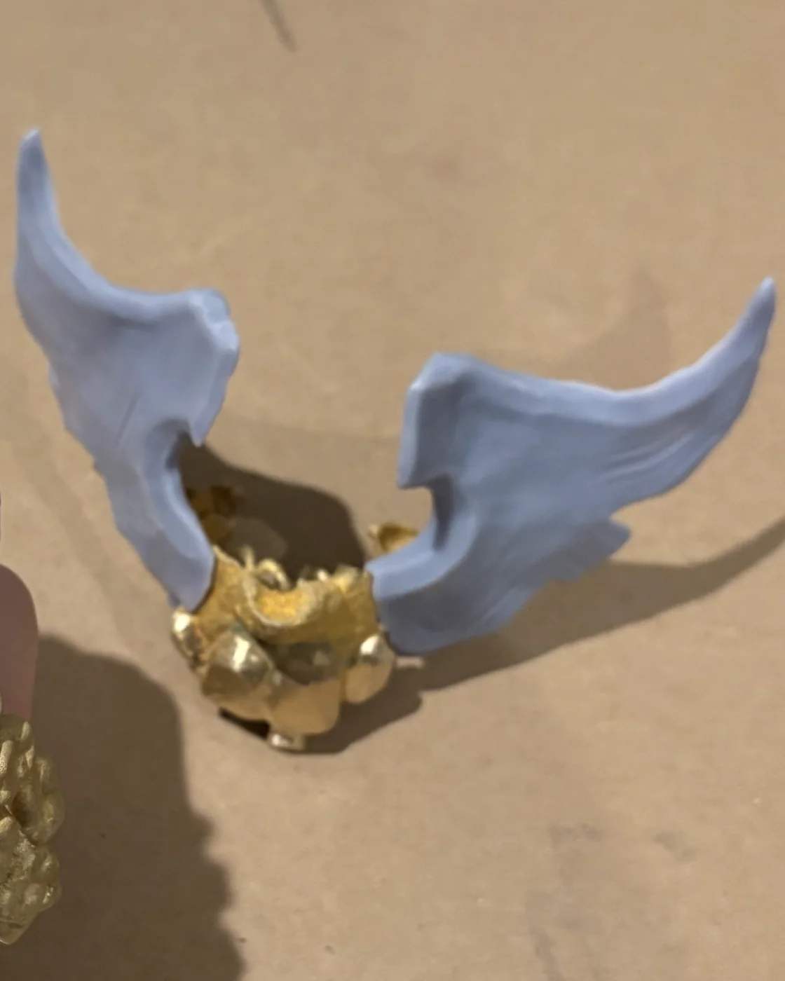 The gold arch standing on a table with a pair of pale blue wings rising from it